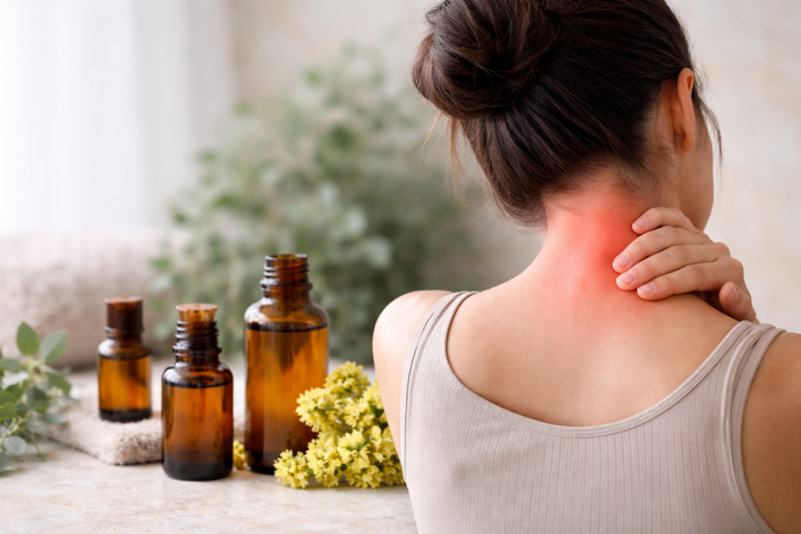 Persona che massaggia la cervicale con tensione muscolare, con oli essenziali sullo sfondo